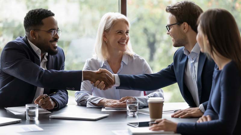 Four business professions meeting with two shaking hands